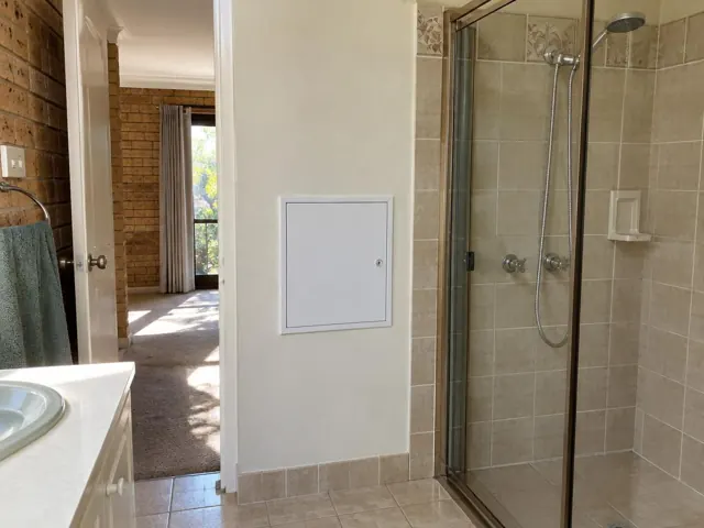 Bathroom wall with a small access panel beside a tiled shower and vanity in Cherrybrook